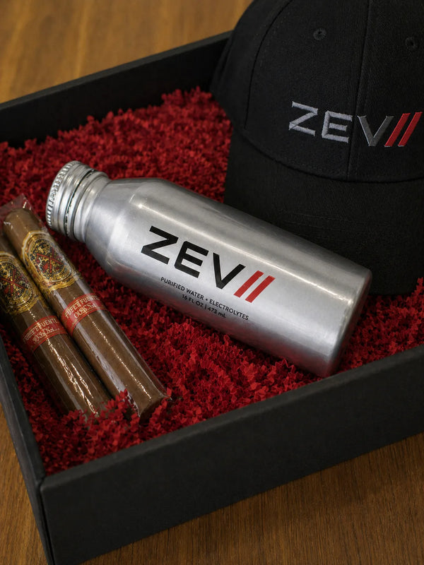 Custom-labeled 16oz aluminum bottled water in a corporate gift box with premium cigars and a branded baseball cap use case